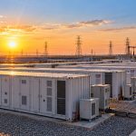 Waaree Renewable: battery storage containers beside a solar farm and transmission towers at sunset