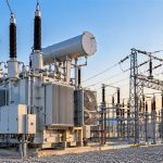 GE Vernova: large power transformer and switchyard equipment at a substation at sunset