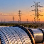 APAR Industries: reels of aluminium conductor beneath transmission towers at sunset